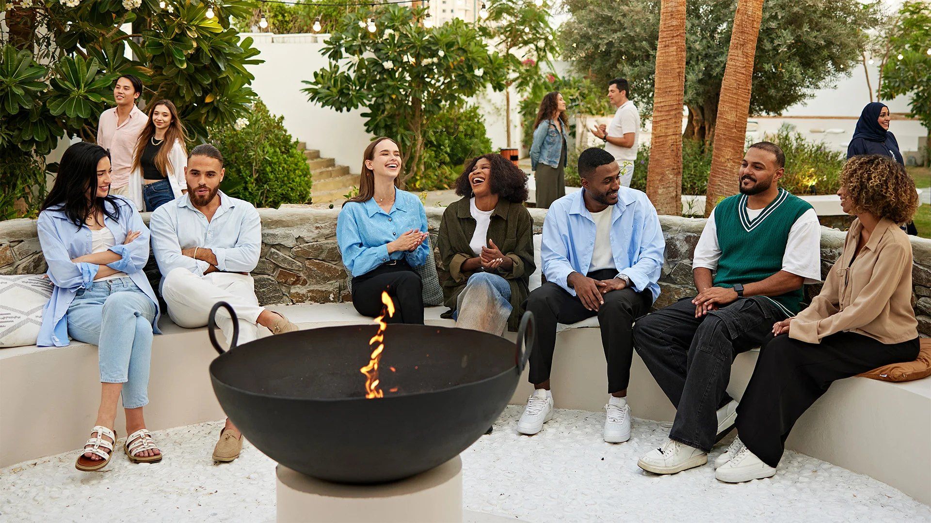 Colleagues laughing together around a fire pit in a resort garden