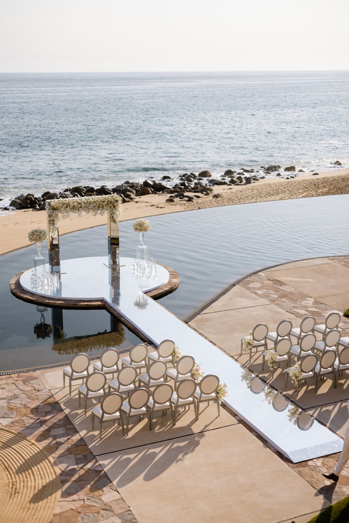 Oceanfront wedding ceremony set beside an infinity pool